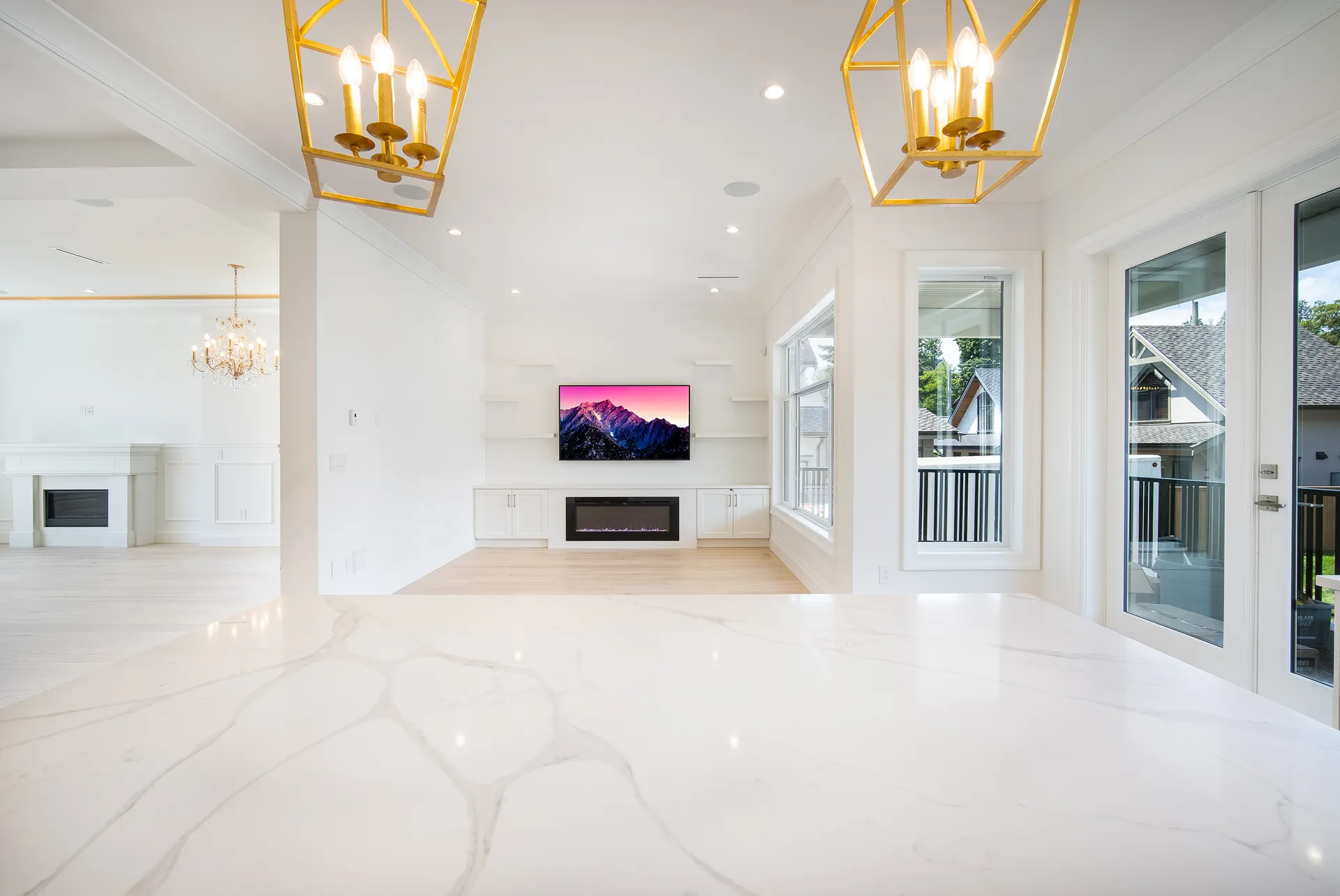 Great room with bookmatched marble floor, twin gold chandeliers, and linear fireplace