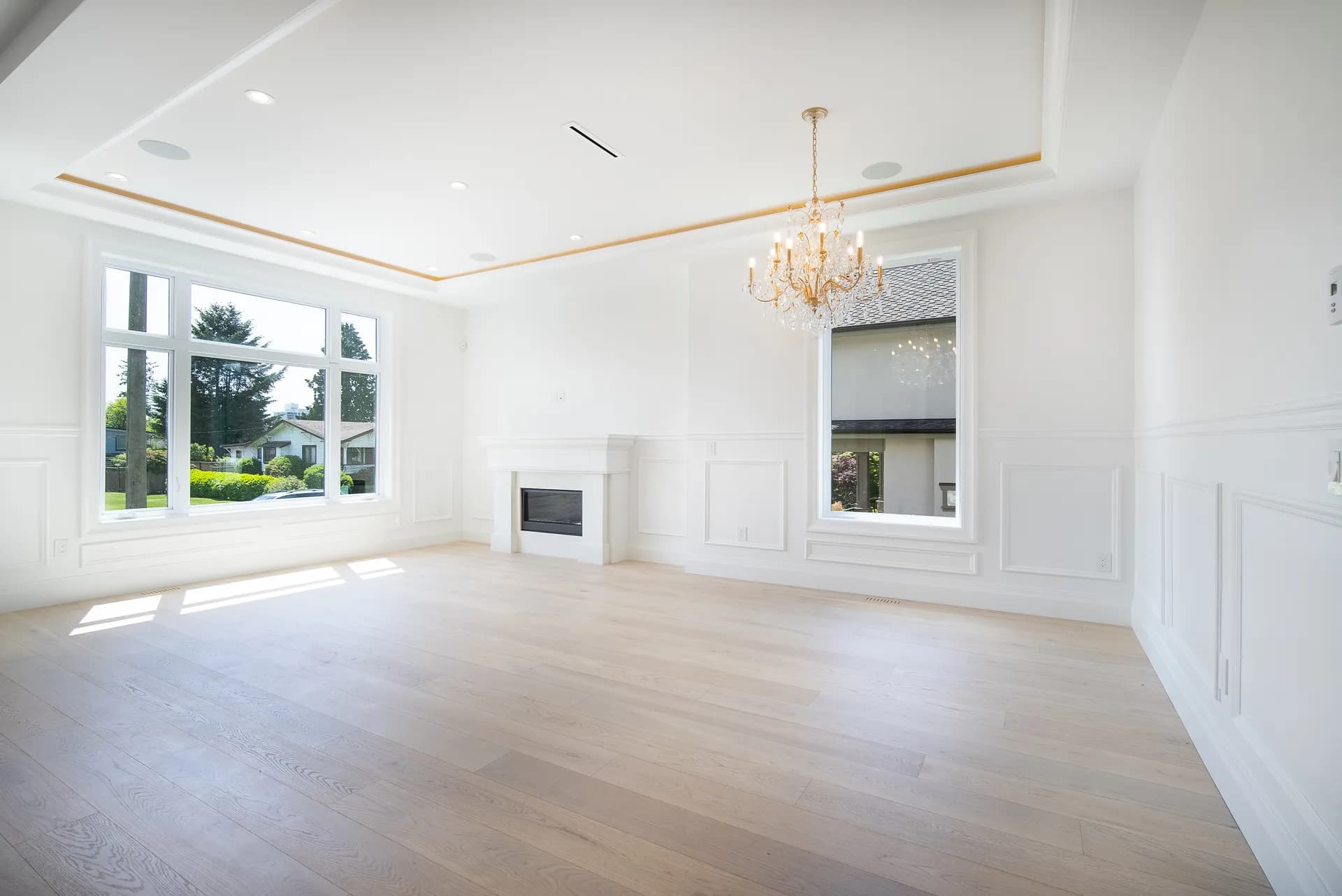 Formal living room with wainscoting, tray ceiling, fireplace, and crystal chandelier
