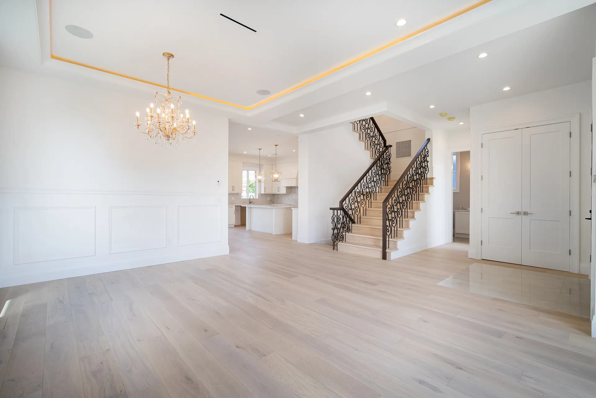 Dining area with panelled walls and curved staircase with iron scroll balusters beyond