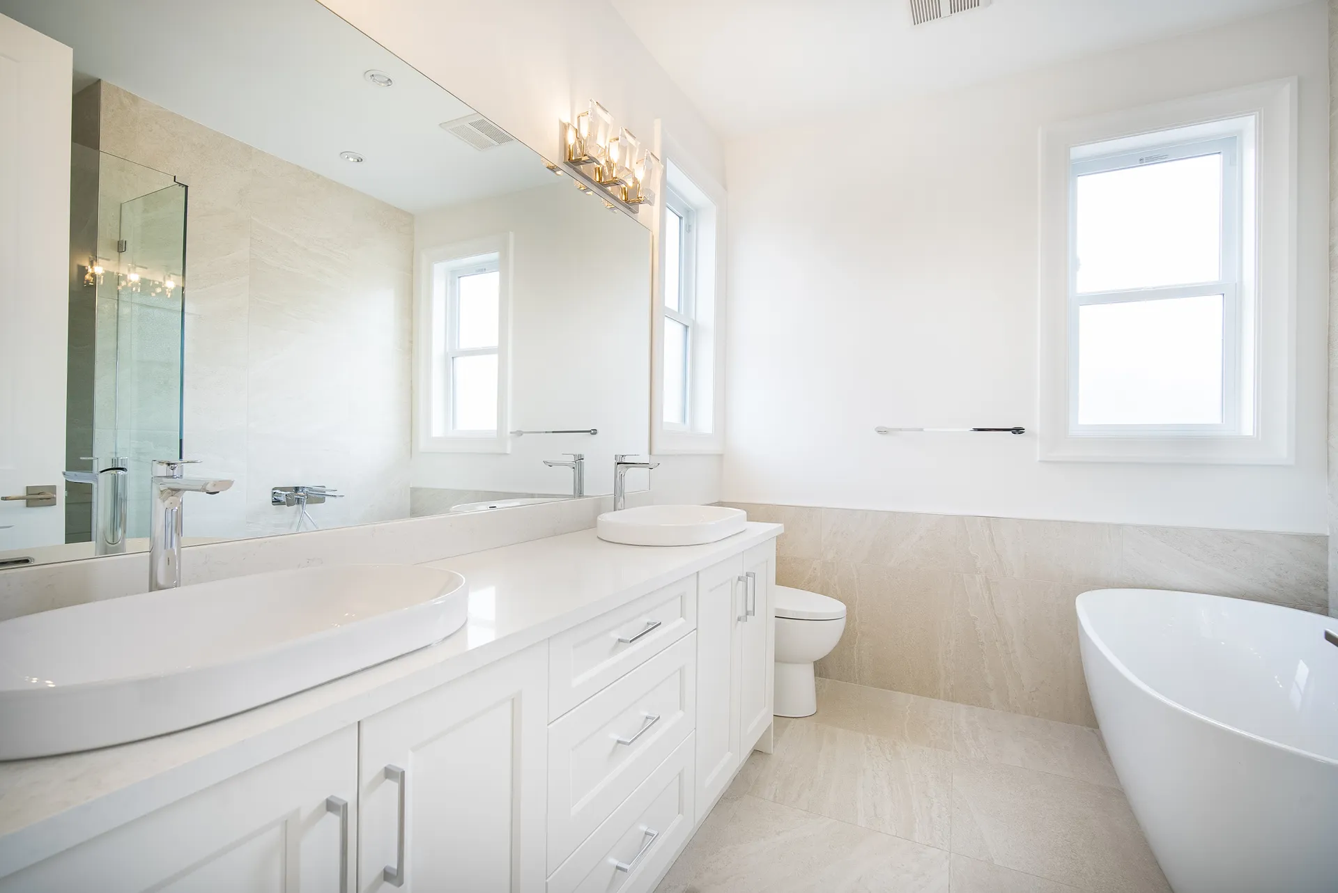 Primary ensuite with double vanity, freestanding tub, and herringbone tile floor