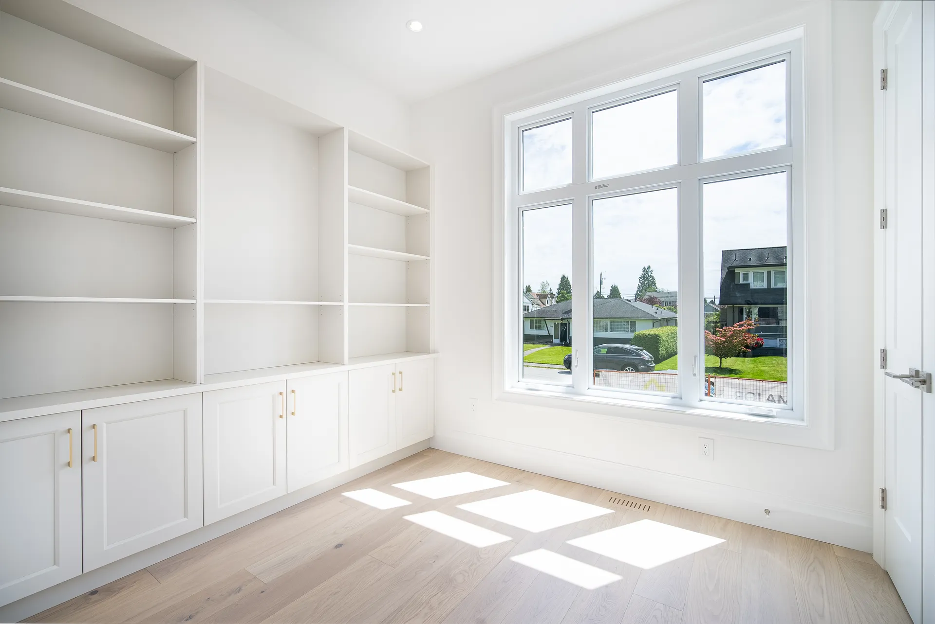 Home office with full wall built-in shelving and large window to the street