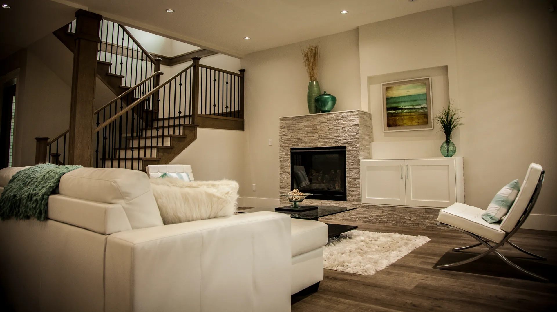 Living room with stacked stone fireplace and wood staircase behind