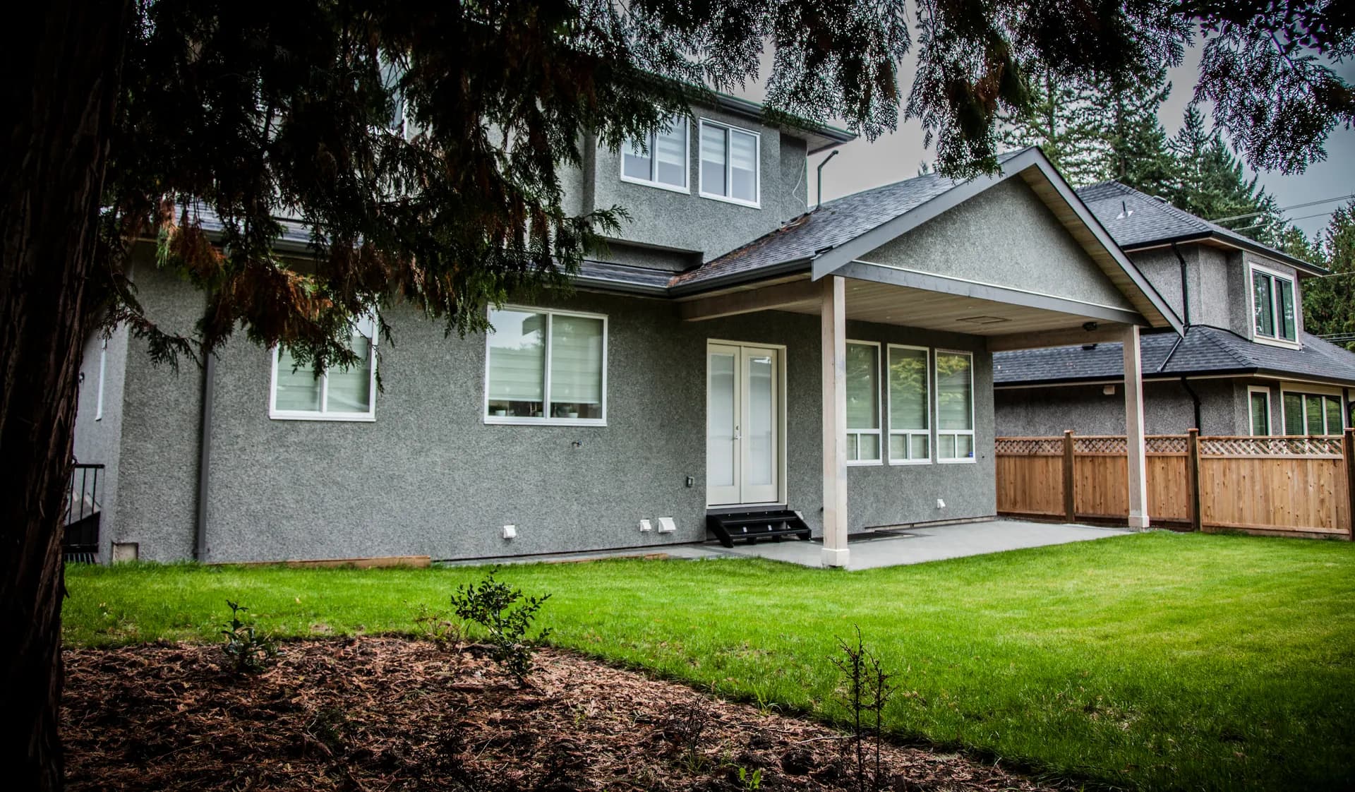 Rear exterior with covered patio, timber posts, and landscaped backyard