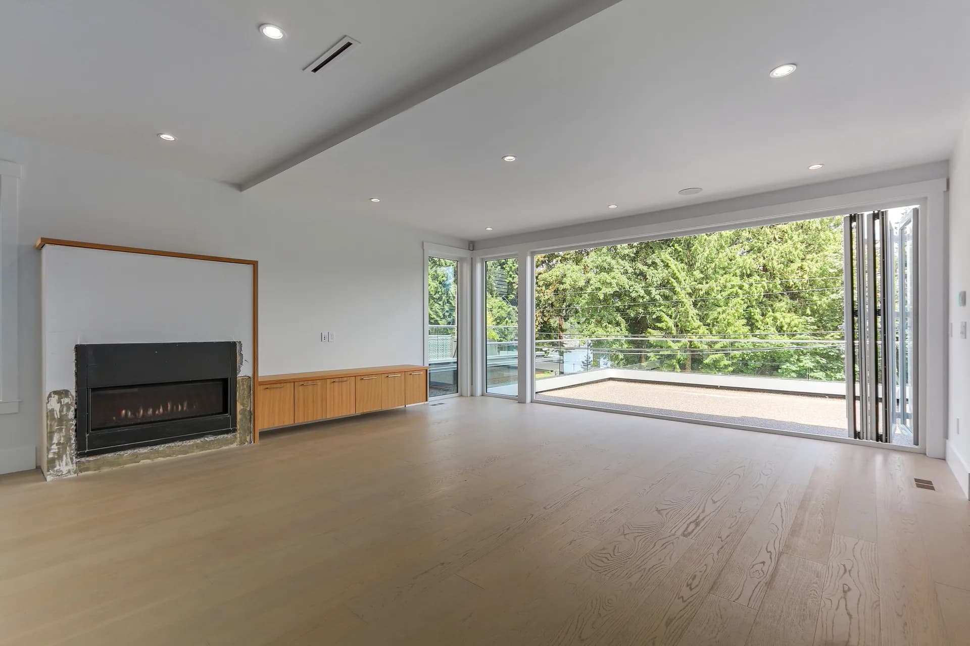 Living room with wood mantel fireplace and folding glass wall open to the deck