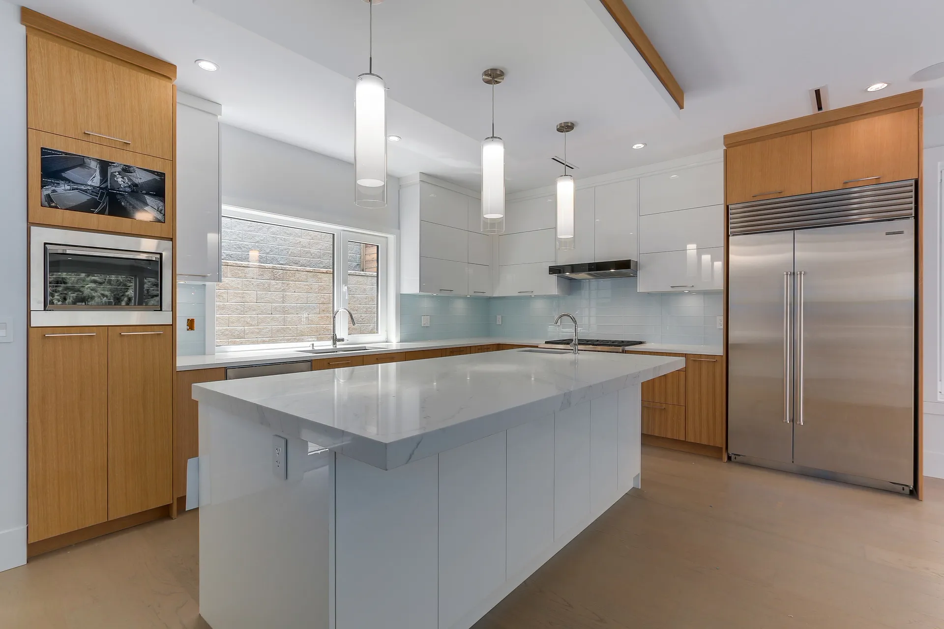 Kitchen with flat panel wood cabinetry, white quartz island, and stainless fridge