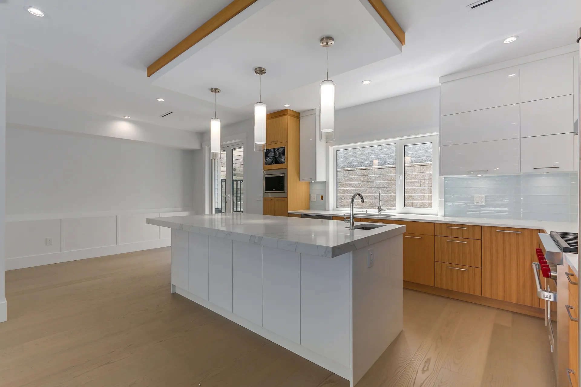 Kitchen island under an exposed wood beam with white pendant lights