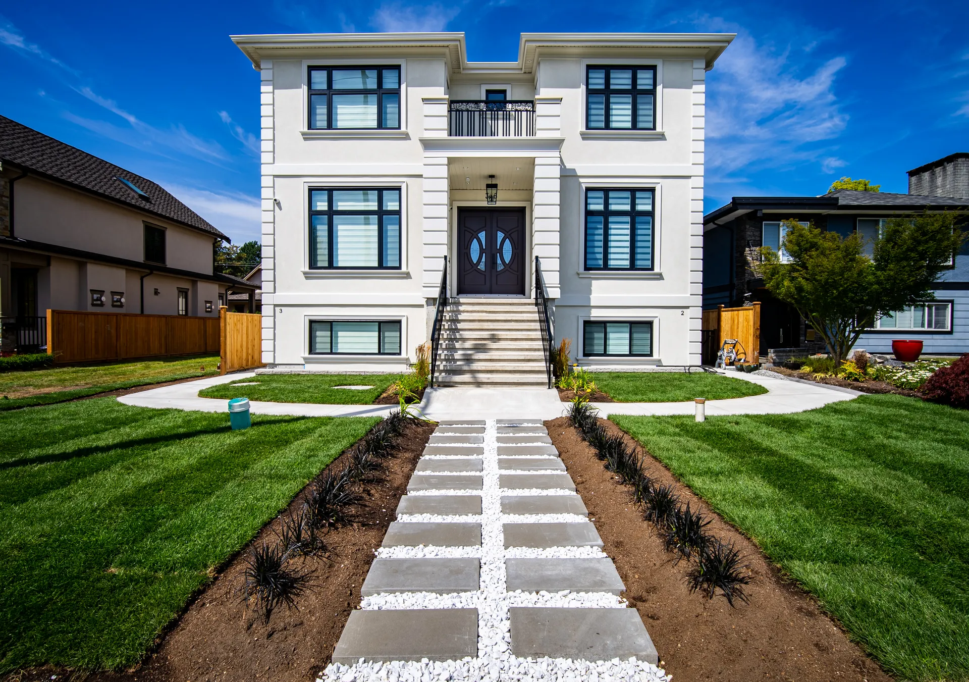 Central Lonsdale Residence, symmetrical white stucco facade with black trimmed windows and grand entry stairs