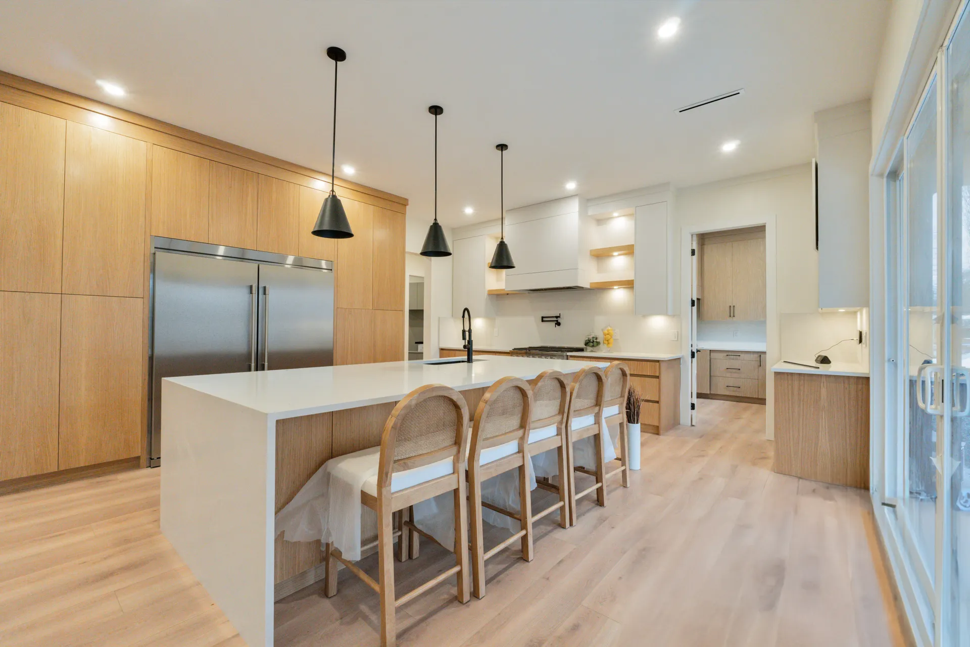Main kitchen with white quartz waterfall island and oak cabinetry in the Langley Modern Estate