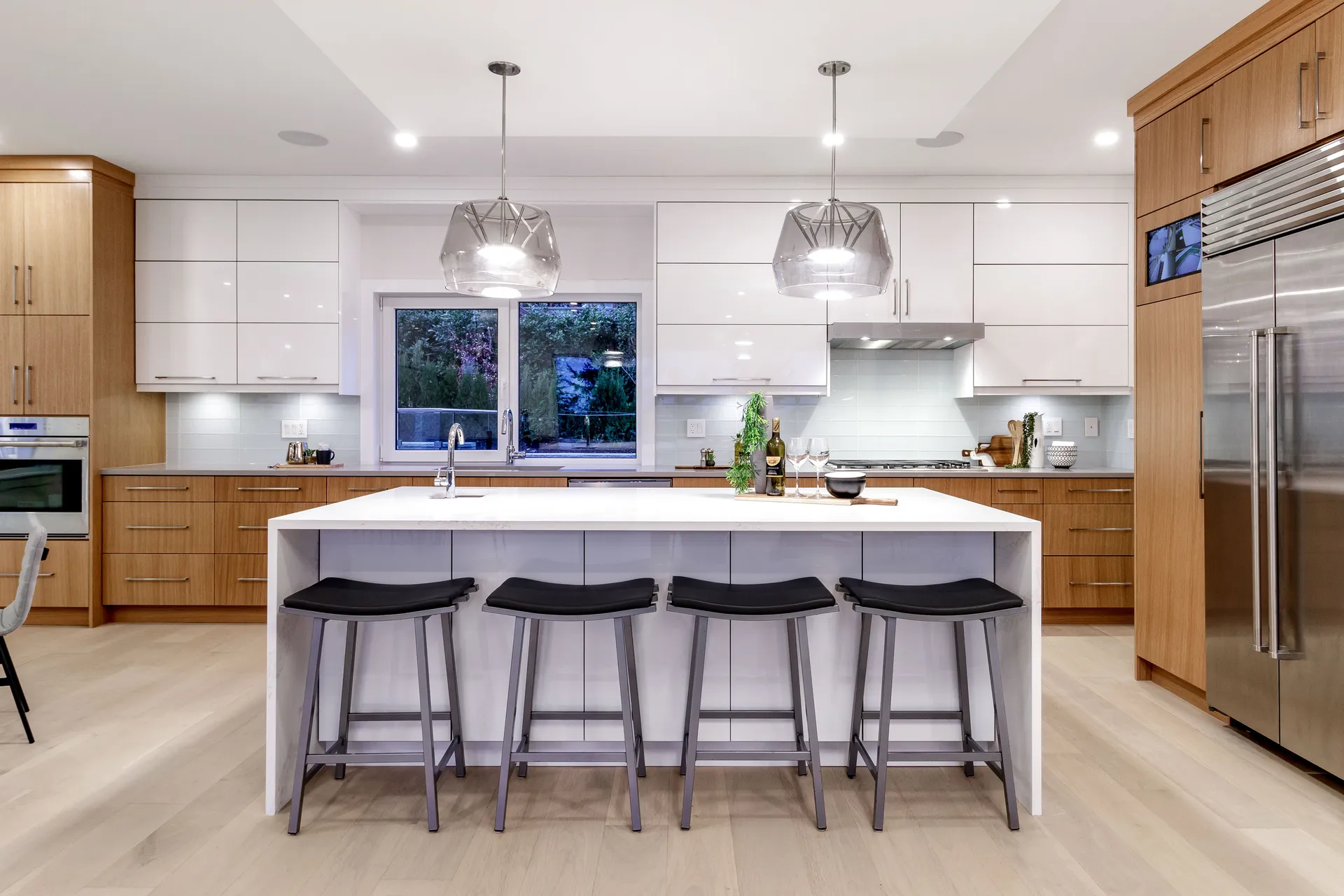 Main kitchen with white quartz waterfall island in a Lynn Valley three storey home